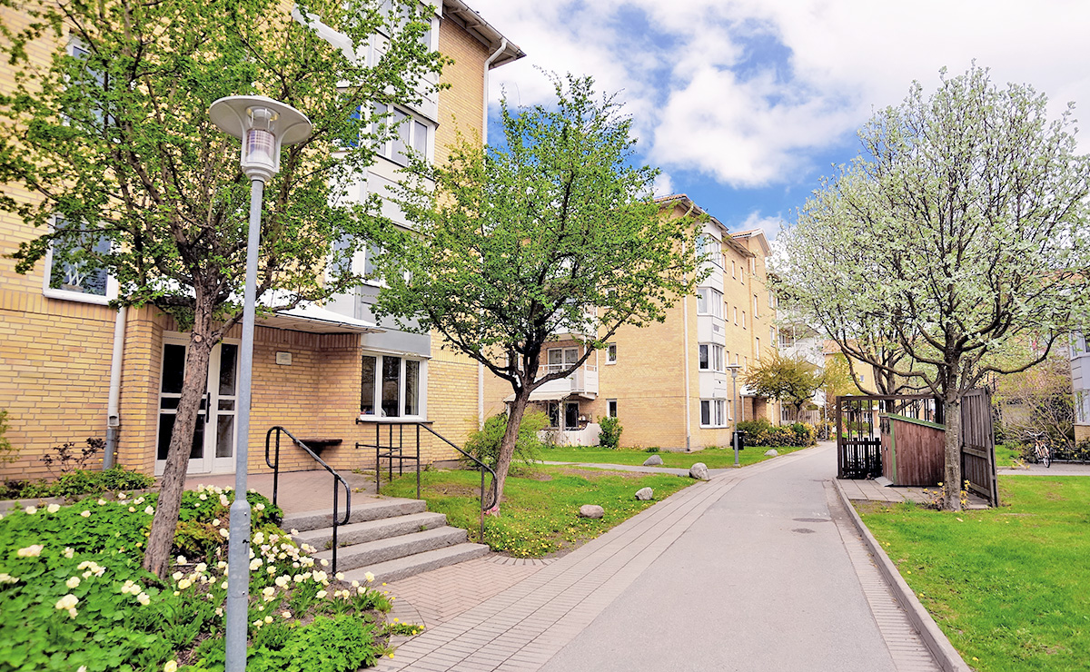 Bild på fastigheter i ett bostadsområde med innergård som grönskar