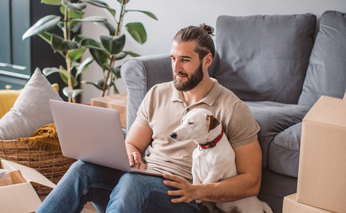 Man som tittar i datorn tillsammans med sin hund