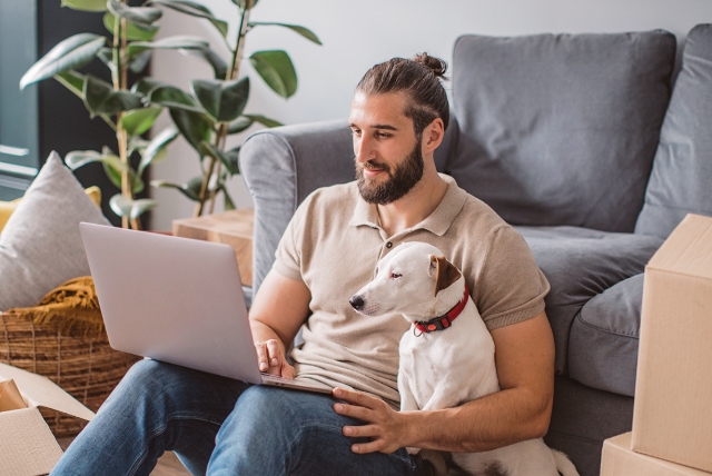 Man som tittar i datorn tillsammans med sin hund